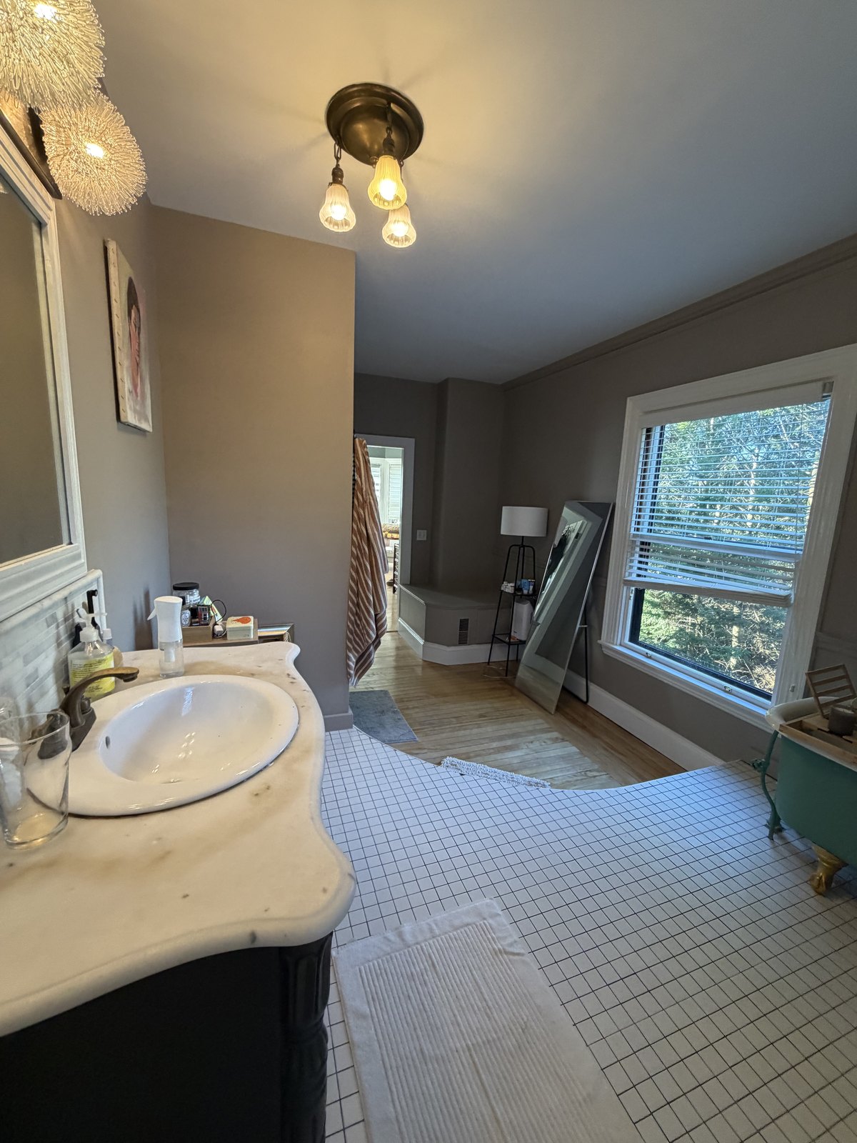 Large bathroom with a marble-topped vanity, white tiled floor and a clawfoot tub, cleaned and dried after a deep clean