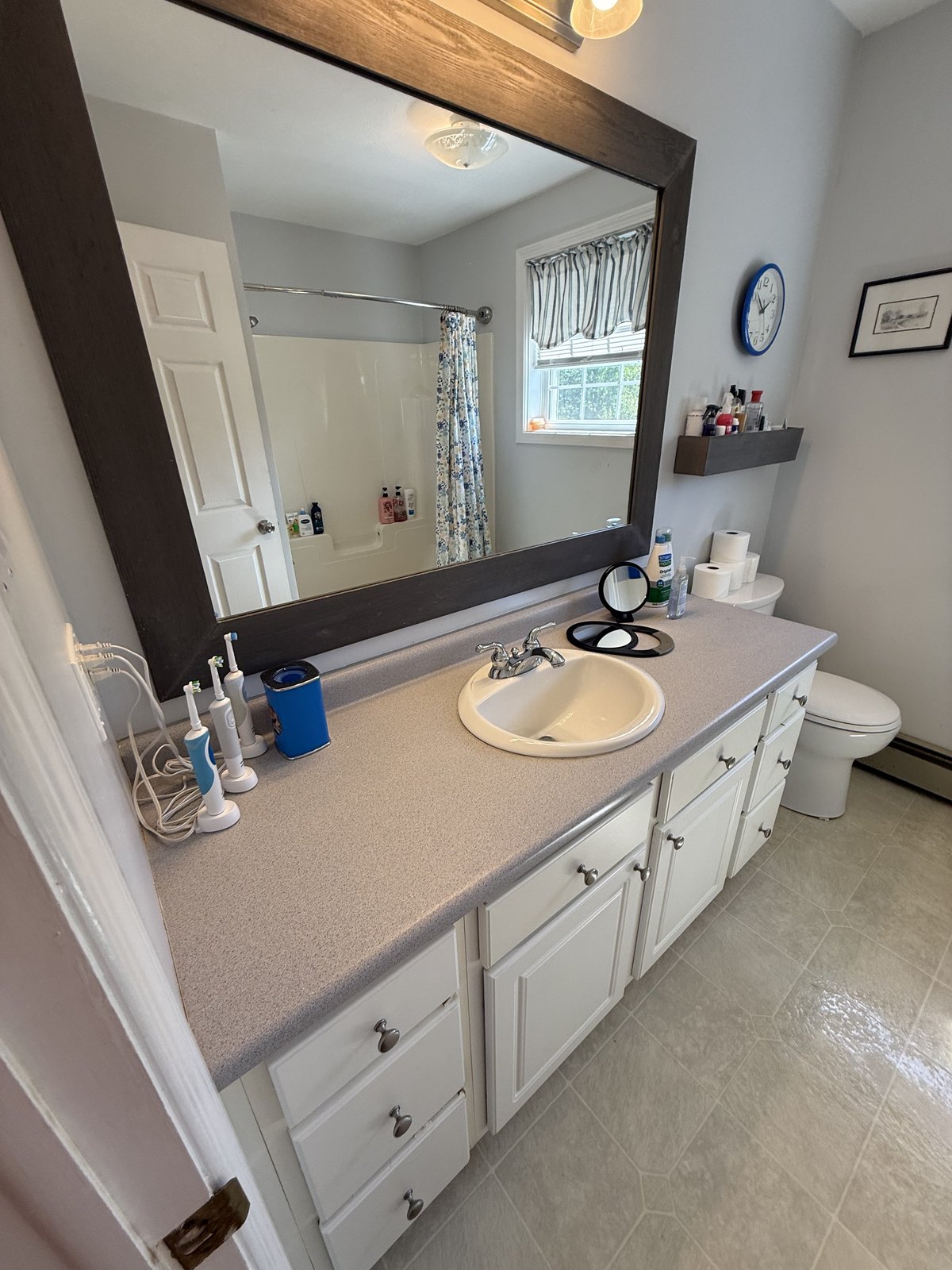 Bathroom vanity with a long countertop, framed mirror and white cabinet doors, wiped clean with the sink and fixtures polished