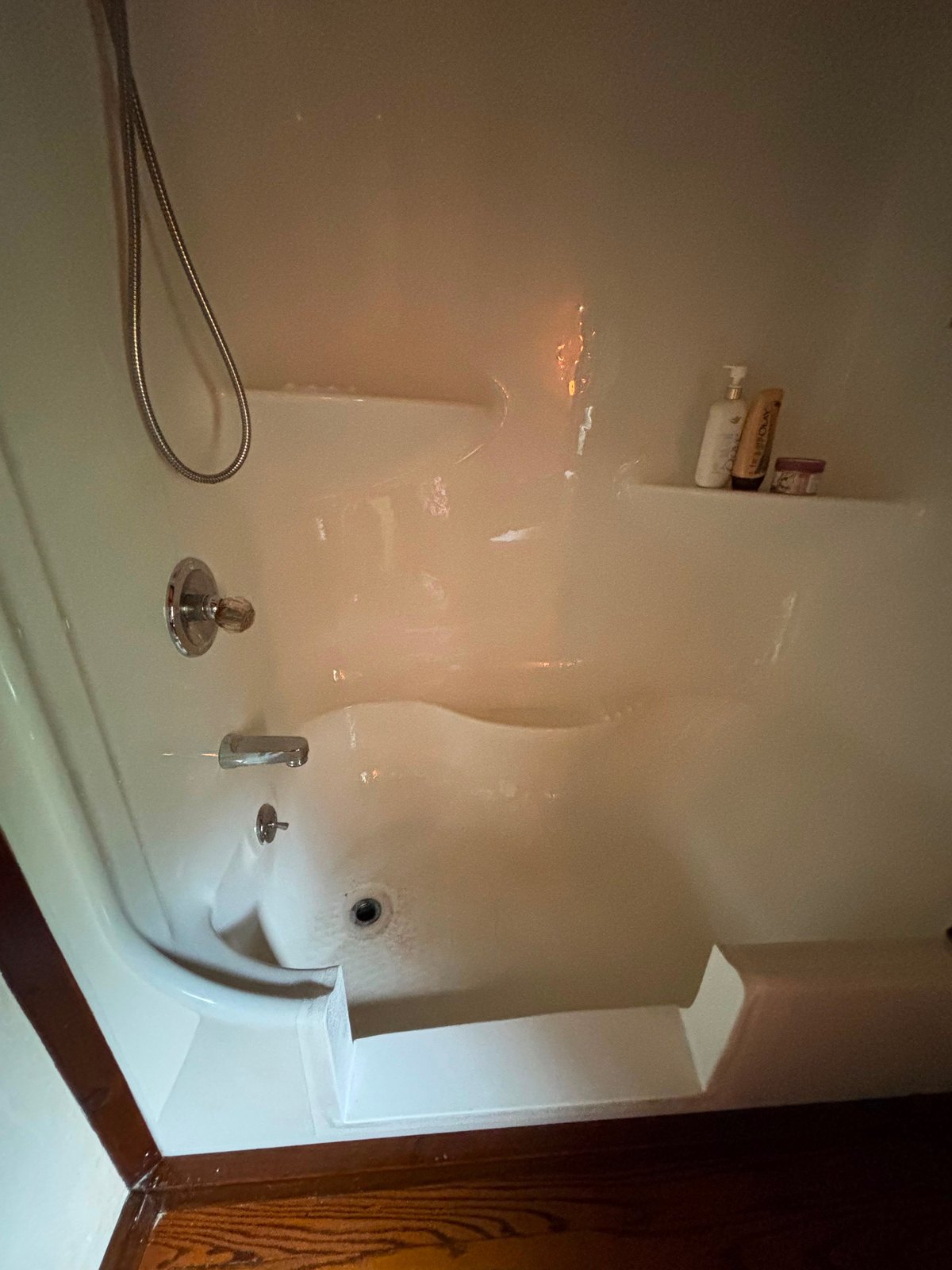 White one-piece tub and shower surround scrubbed clean, with the soap shelf cleared and the fixtures polished