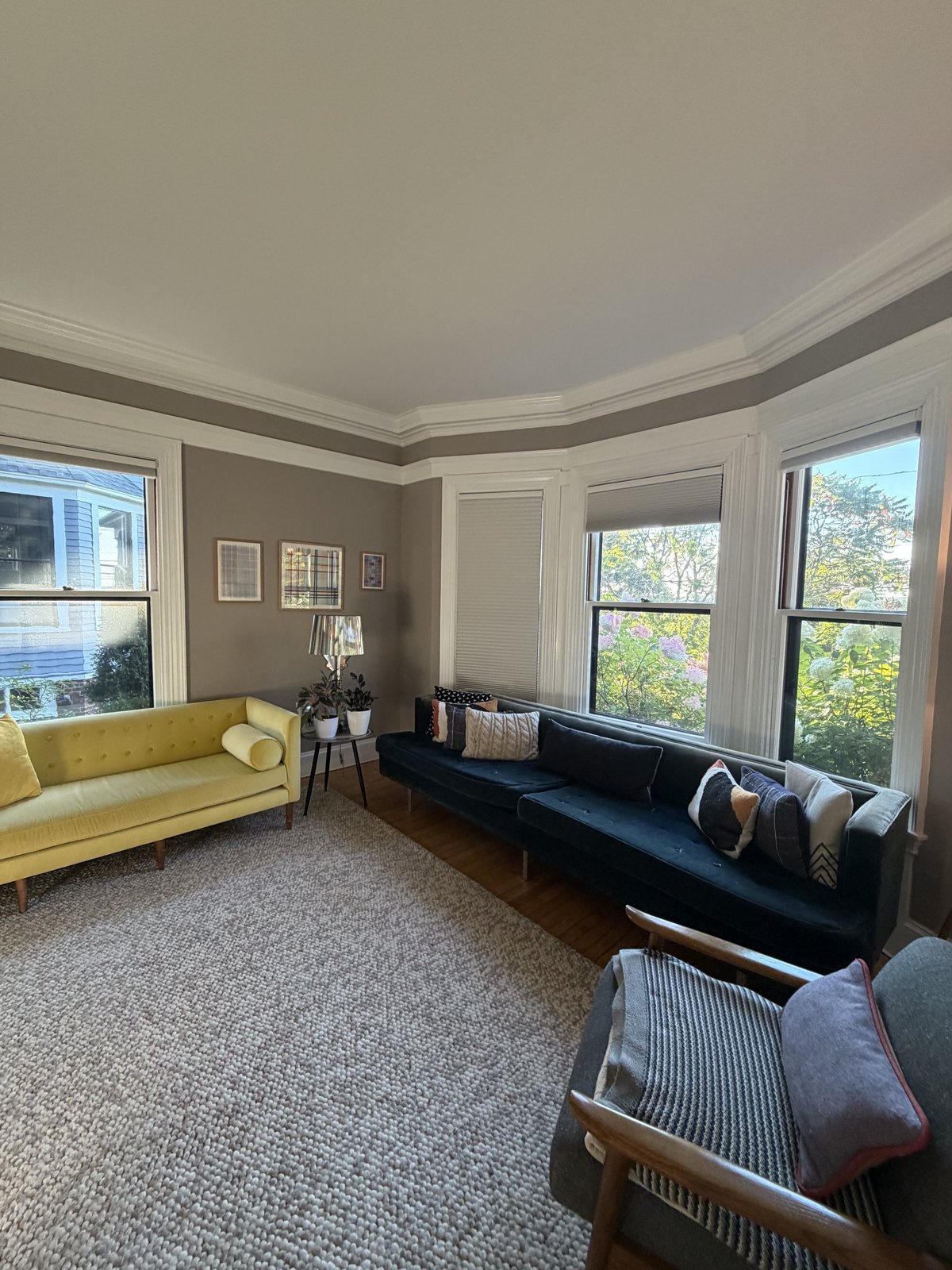 Living room with a bay window, yellow and navy sofas and a looped wool rug, dusted and vacuumed after a house cleaning visit