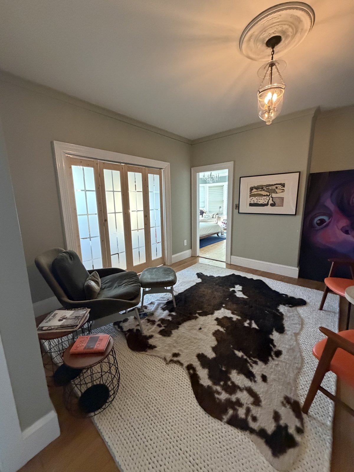 Small den with French doors, a cowhide rug over a woven rug and a reading chair, vacuumed and dusted after a house cleaning visit