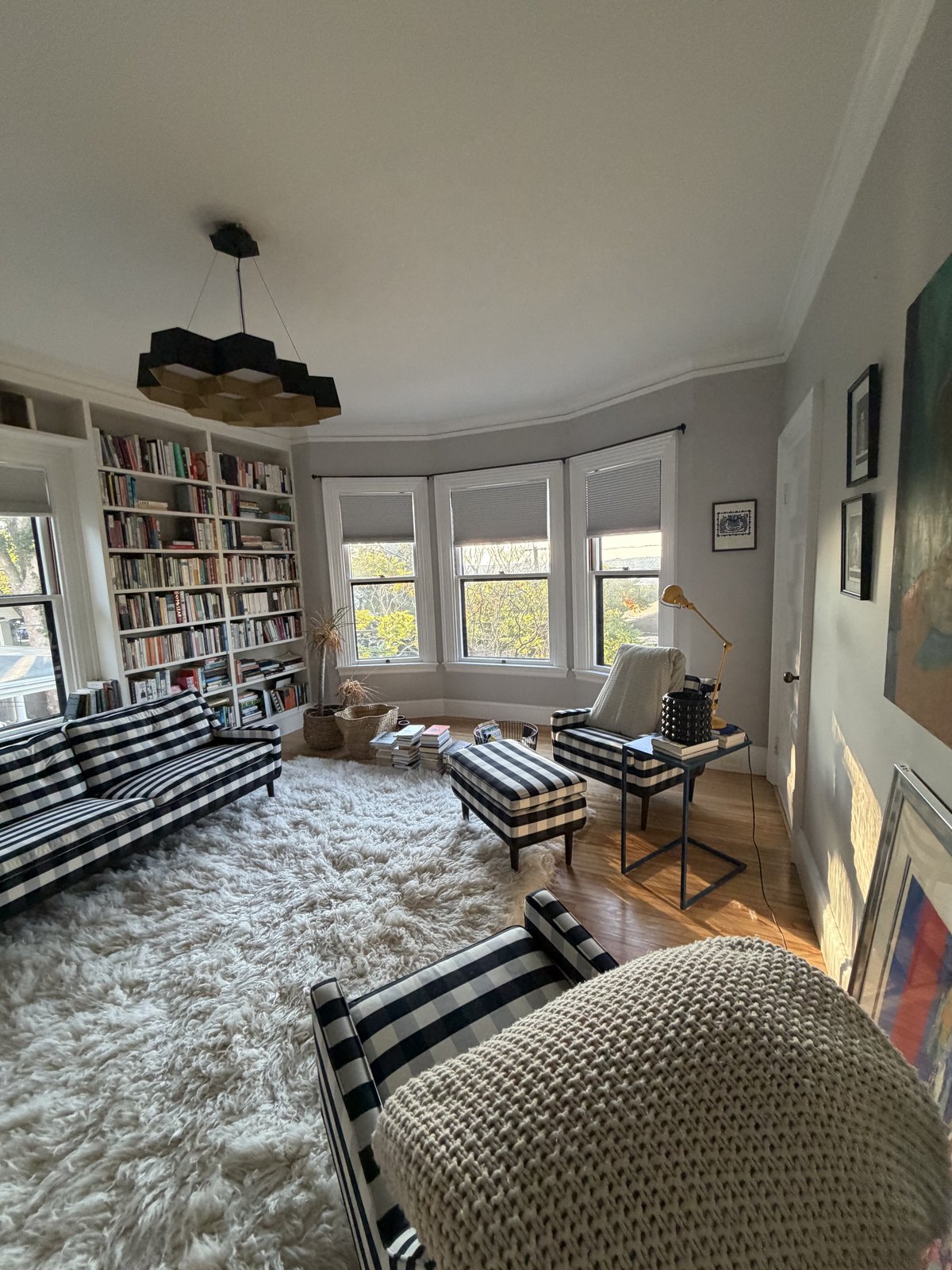 Library sitting room with floor-to-ceiling bookshelves, striped armchairs and a shaggy white rug, cleaned and vacuumed
