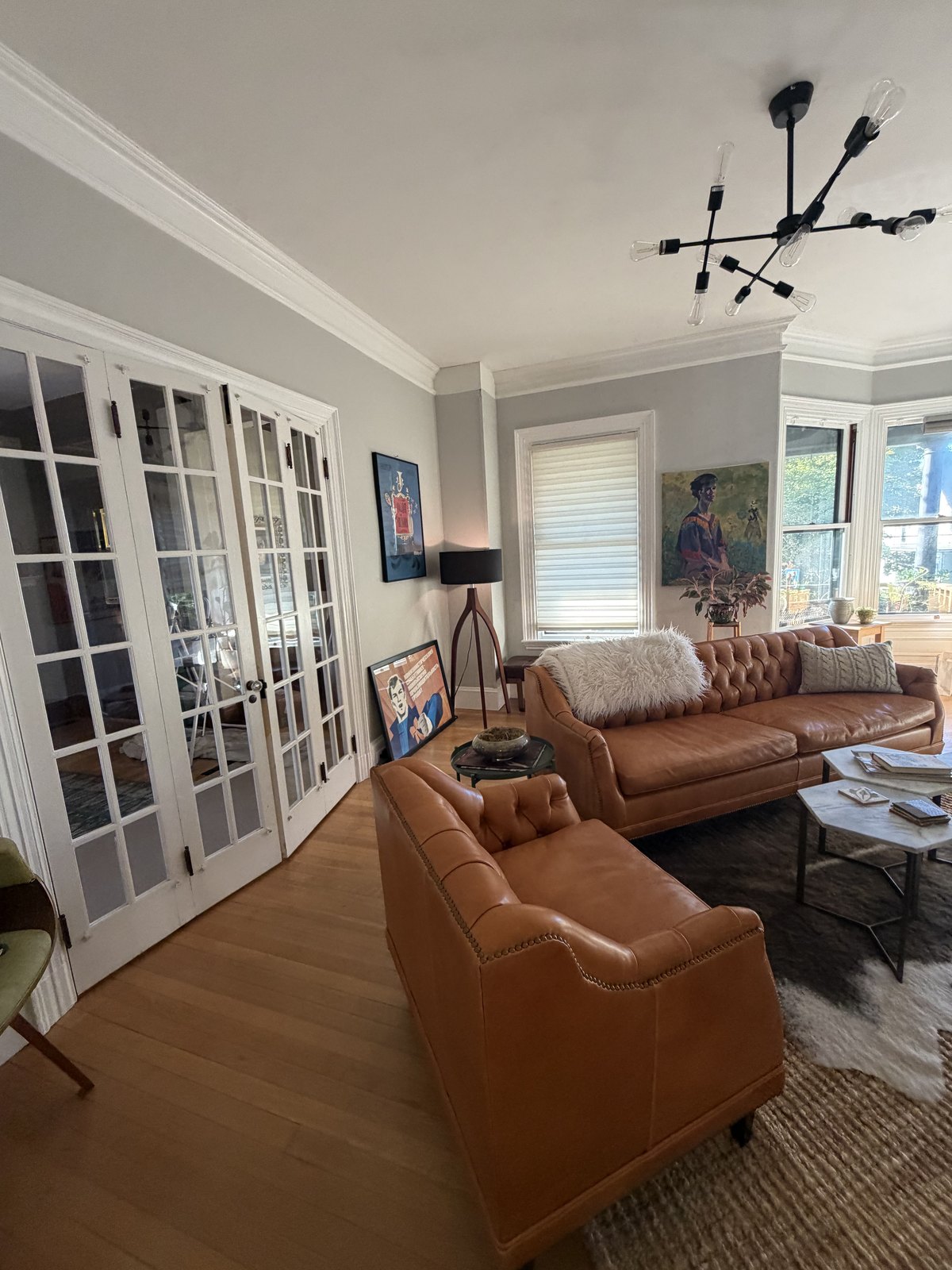 Living room with tan leather sofas, French doors and hardwood floors, dusted and vacuumed after a house cleaning visit